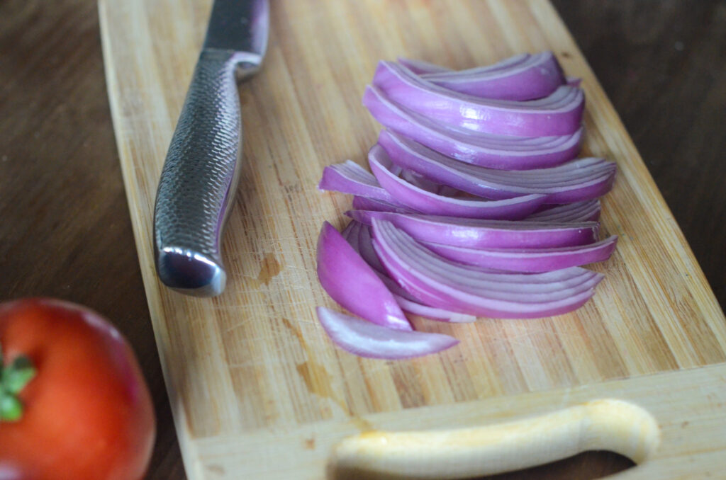 chopped purple onion on cutting board with knife