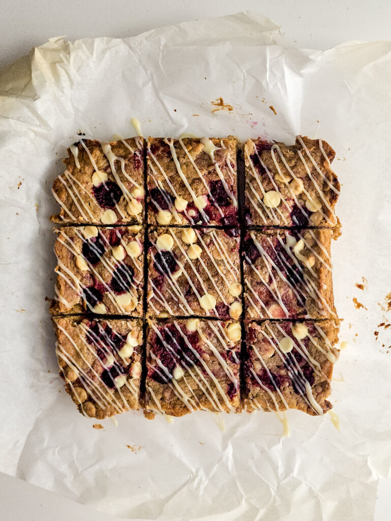 white chocolate raspberry blondies cut into squares on parchment paper
