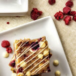 white chocolate raspberry blondies on white square plate