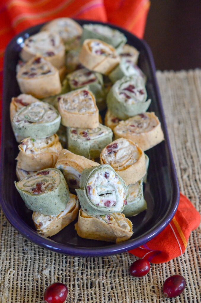 cranberry bacon tortilla roll ups on a purple tray with red napkin under