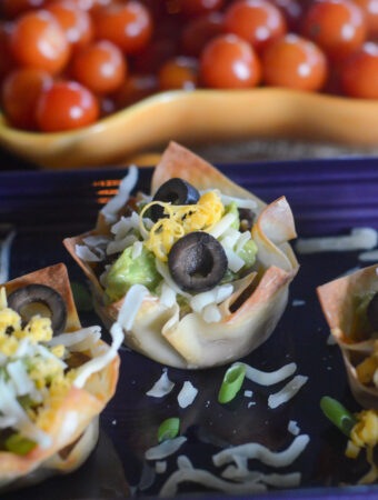 fiesta guacamole wonton taco cups with cherry tomatoes at back