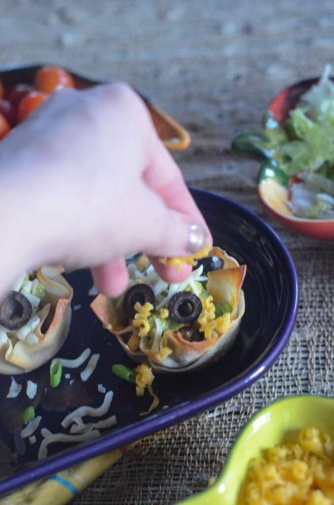 woman sprinkles cheese on guacamole wonton taco bites