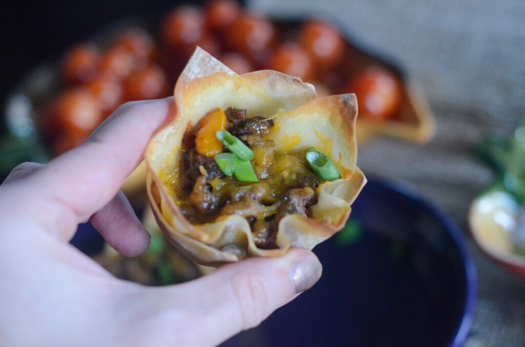 woman holds wonton taco appetizer