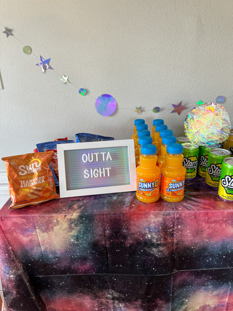 outta sight letter board on a galaxy party table (outer space party table) with Sun Chips and Sunny D