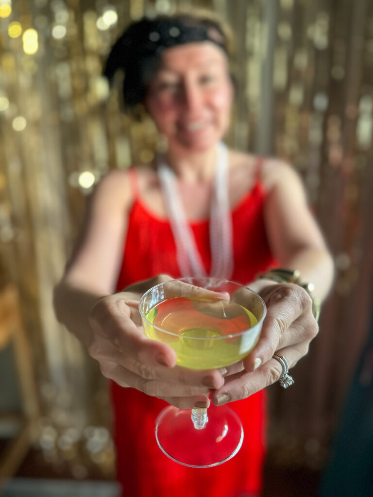 woman in red dress holds a 1920s cocktail at a murder mystery 1920s party