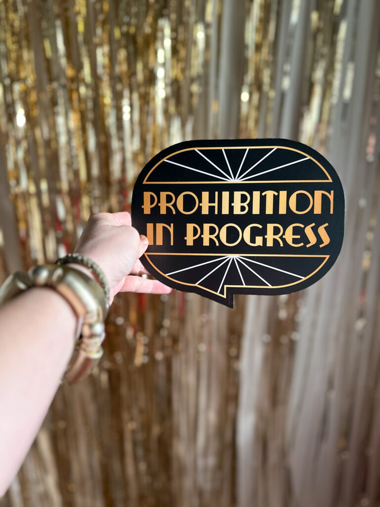 woman holds Prohibition sign in front of gold fringe