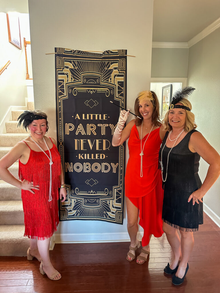women standing in front of a "a little party never killed nobody" sign