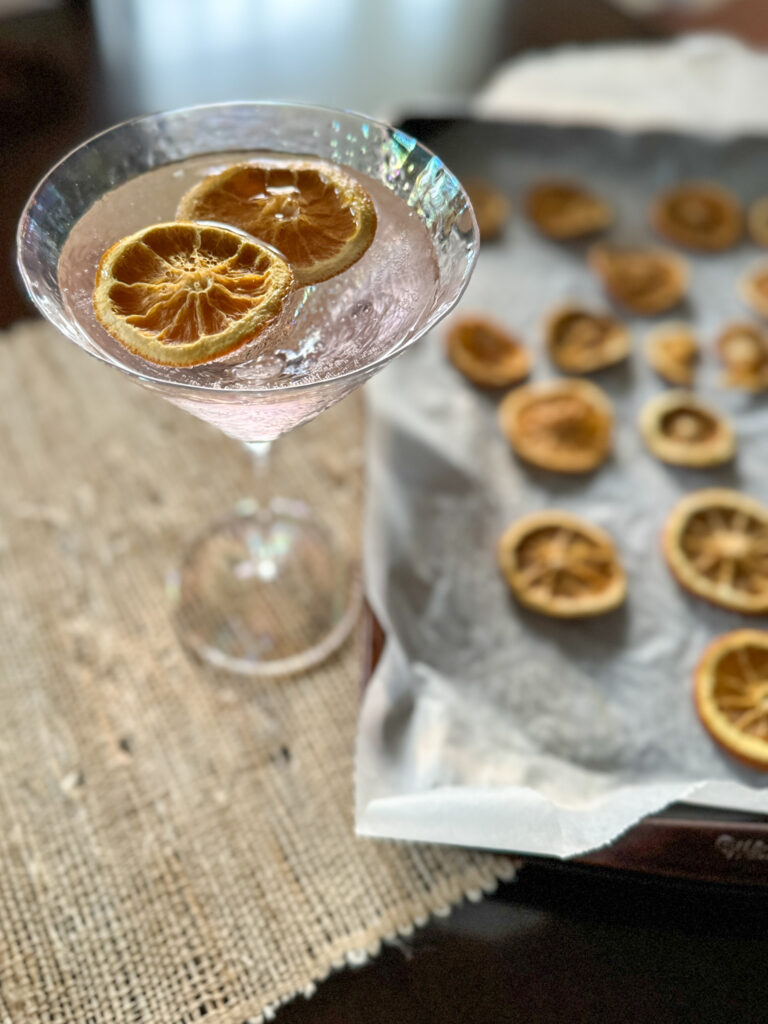 pink lemonade gin cocktail beside a tray of dehydrated lemons 