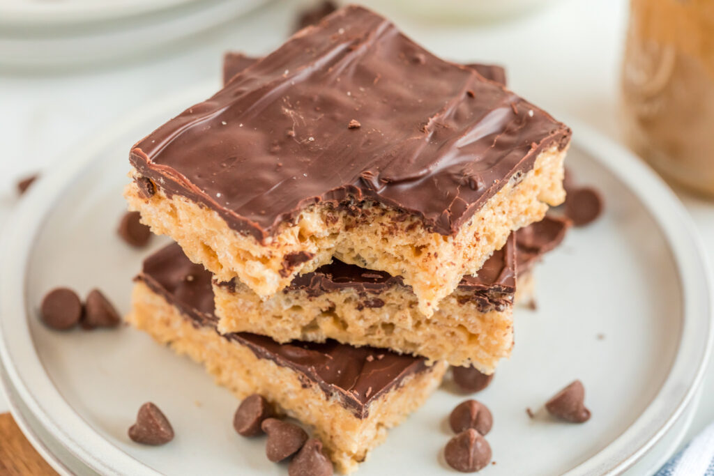 three chocolate peanut butter Rice Krispie treats on two stacked white plates