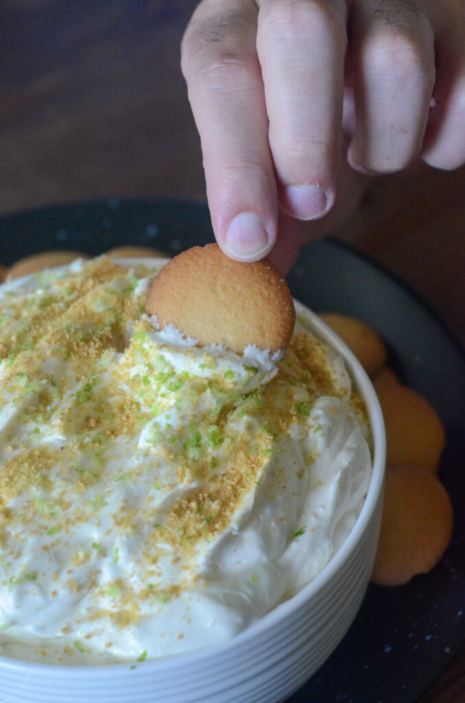 no bake key lime cheesecake dip (key lime pie dip) being dipped with a vanilla wafer 