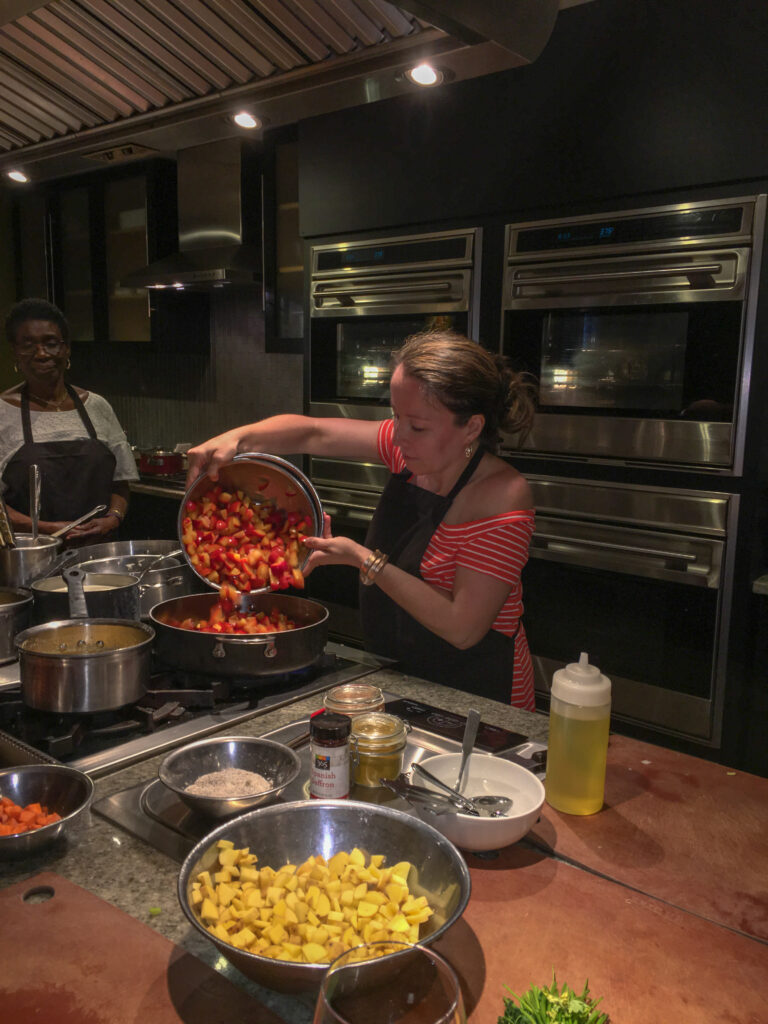 Arkansas lifestyle blogger, Amy, pours a vegetable dish at a Savannah cooking class