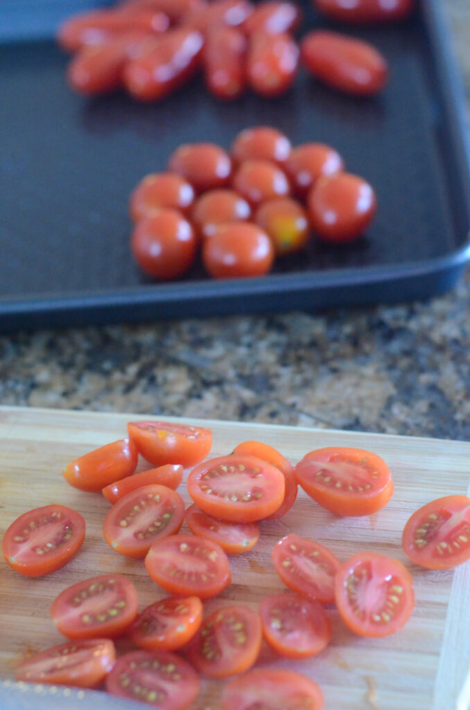 cherry tomatoes sliced in half on cutting board