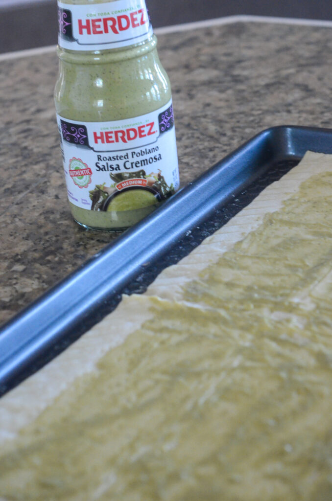 bottle of Herdez Roasted Poblano Salsa Cremosa beside baking pan