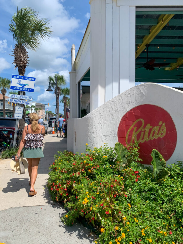 woman walks beside Rita's Seaside Grille in Folley Beach