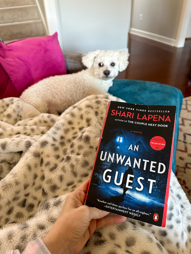 woman reads a snow storm thriller with white dog near her feet