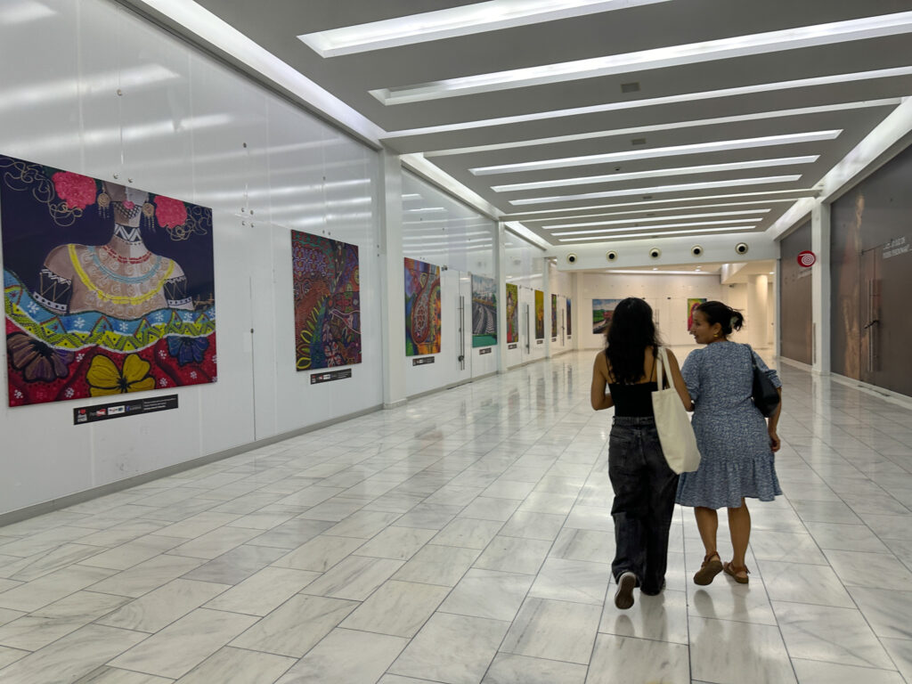 women walking past art exhibits in Albrook Mall in Panama City, Panama