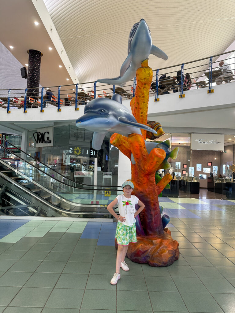 girl stands in front of Dolphin statue in Dolphin hall of Albrook Mall in Panama City