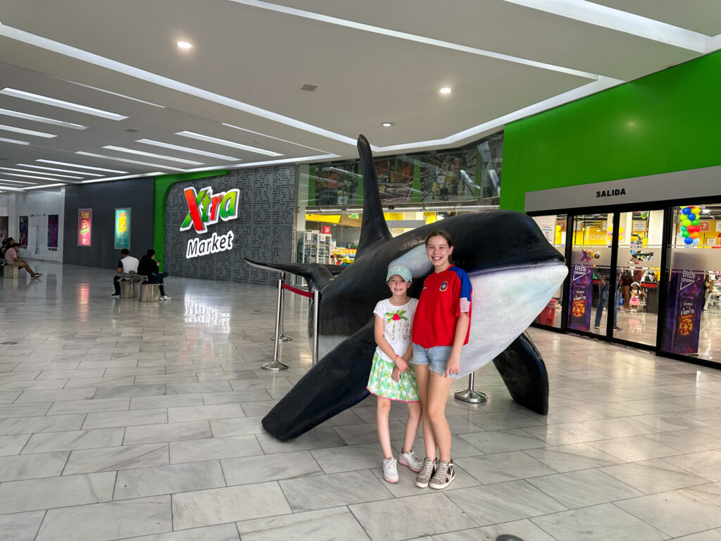 girls standing next to an Orca statue