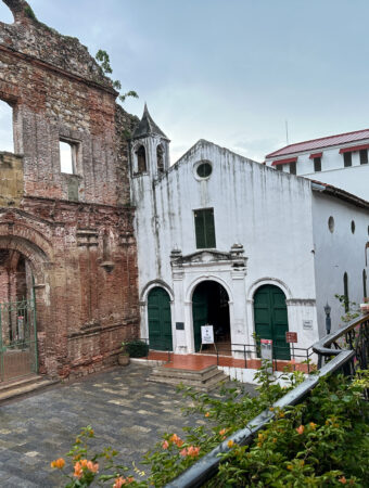 woman drinks coffee on balcony of her Panama City, Panama apartment for rent in Casco Viejo while looking at Arco Chato ruins