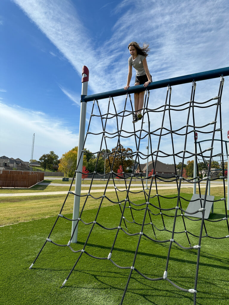 girl at the top of playground structure at Shaw Family Park in Springdale