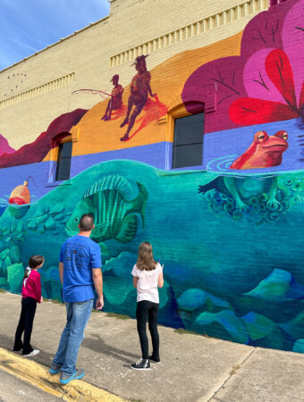 dad and daughters look at mural in downtown Springdale