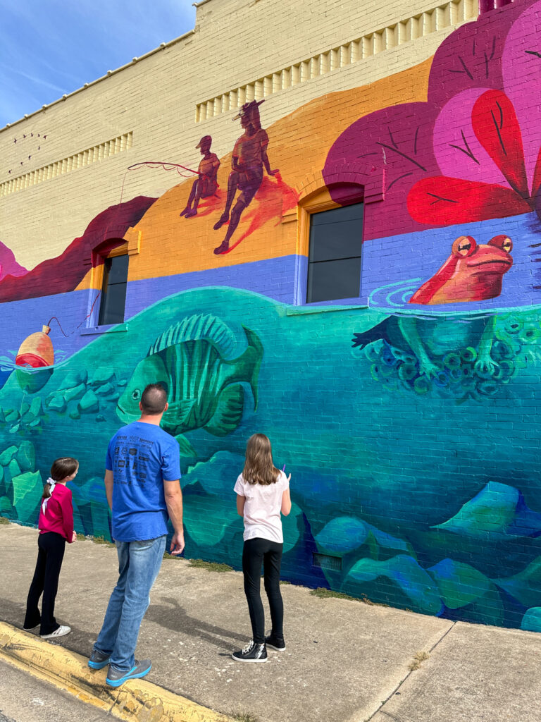 dad and daughters look at mural in downtown Springdale