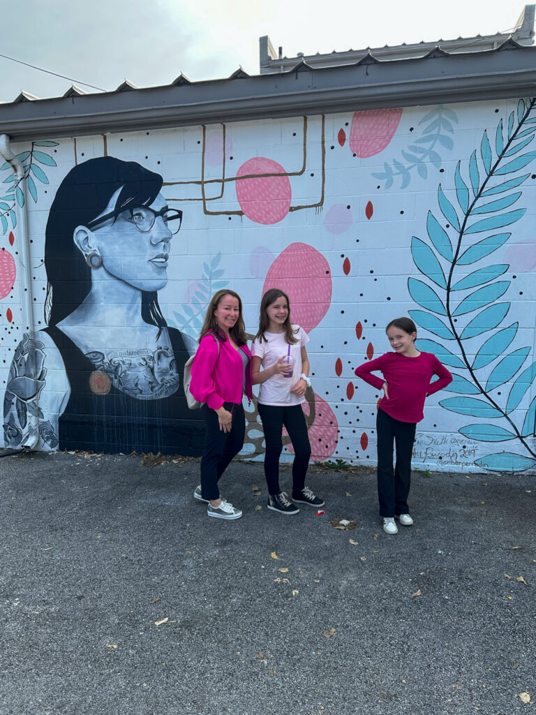 mom and daughters standing in front of mural in downtown Springdale