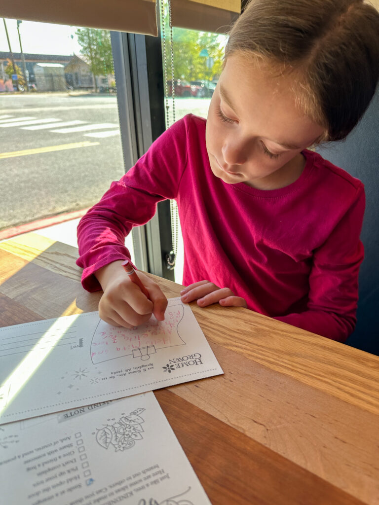 little girl writing a postcard at HomeGrown in Springdale