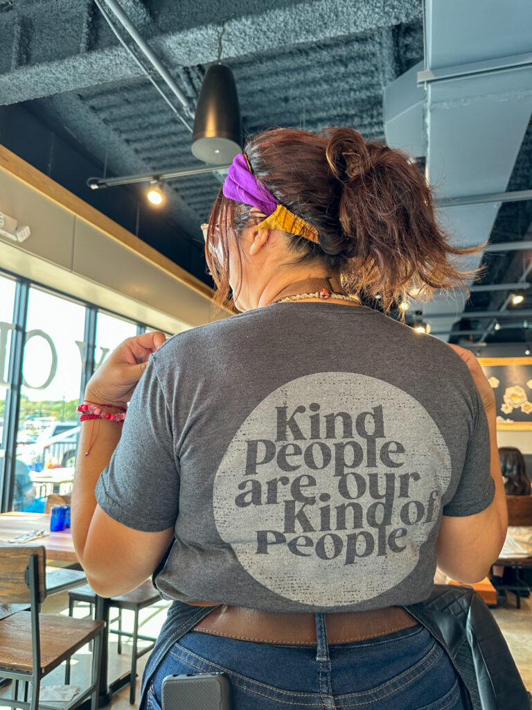 waitress shows back of kindness t-shirt