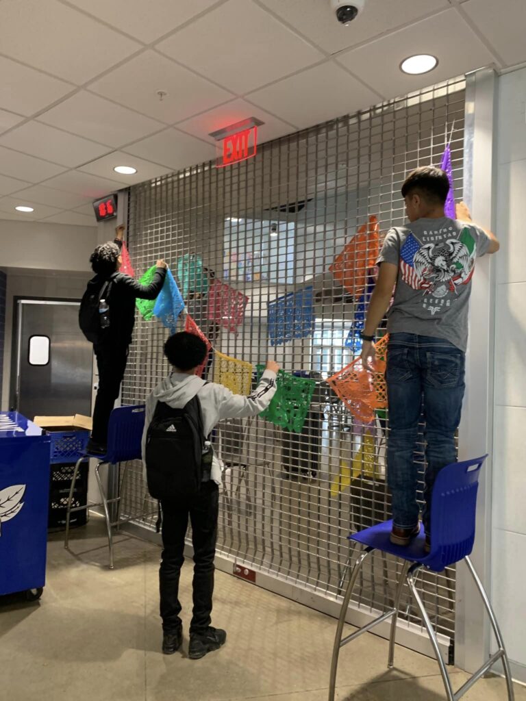 boys hanging Hispanic Heritage Month banner in school cafeteria