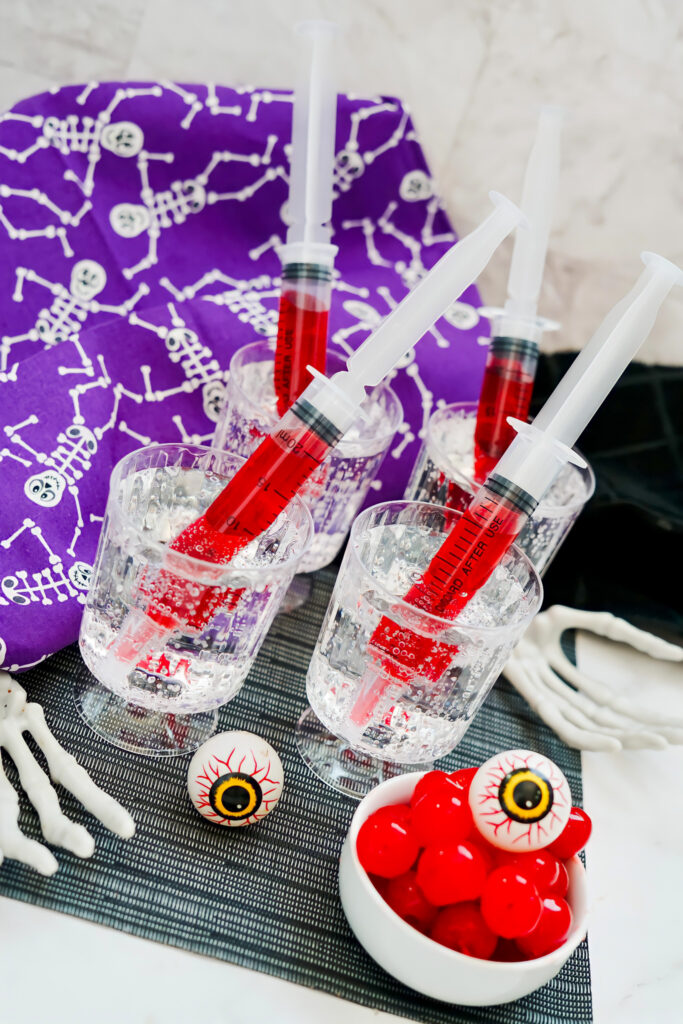 Halloween syringe drinks on table with eyeballs