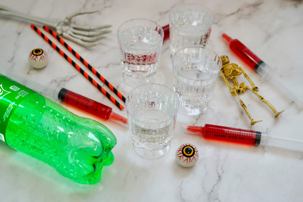 Halloween syringe cocktails spread out on counter