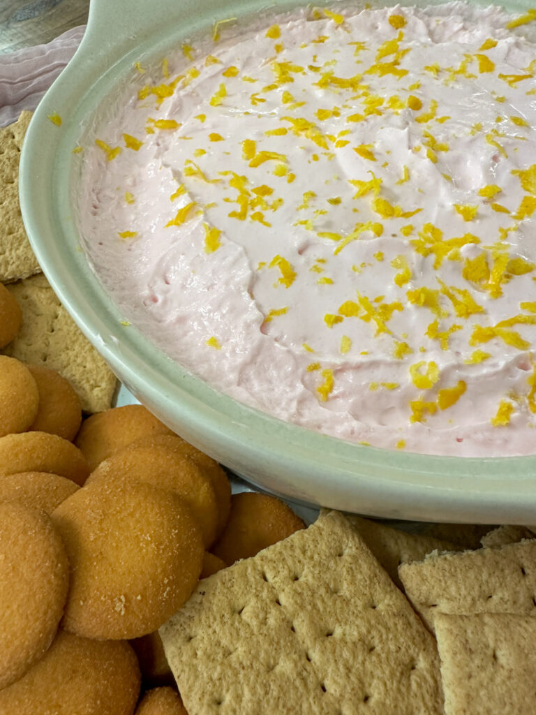 pink lemonade dip in cream colored bowl with crackers around