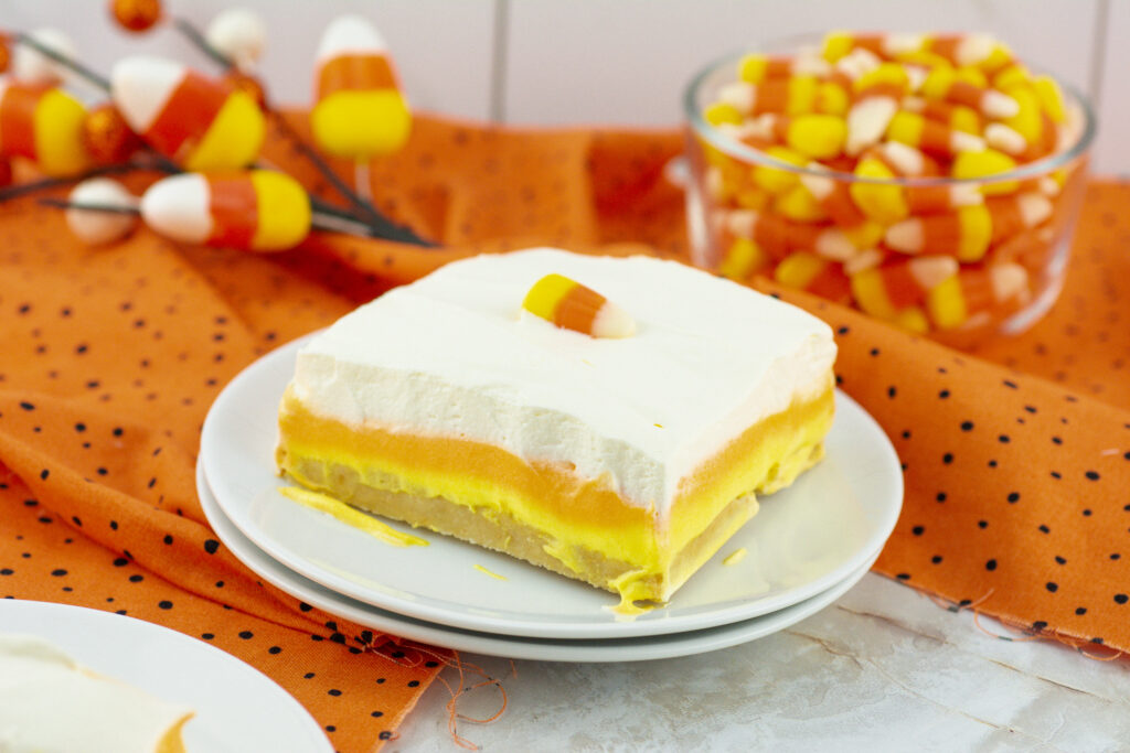 lush candy corn dessert plated beside bowl of candy corn