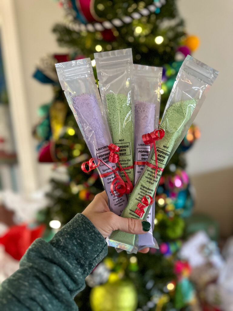 woman holds popsicle bath salts in front of Christmas tree