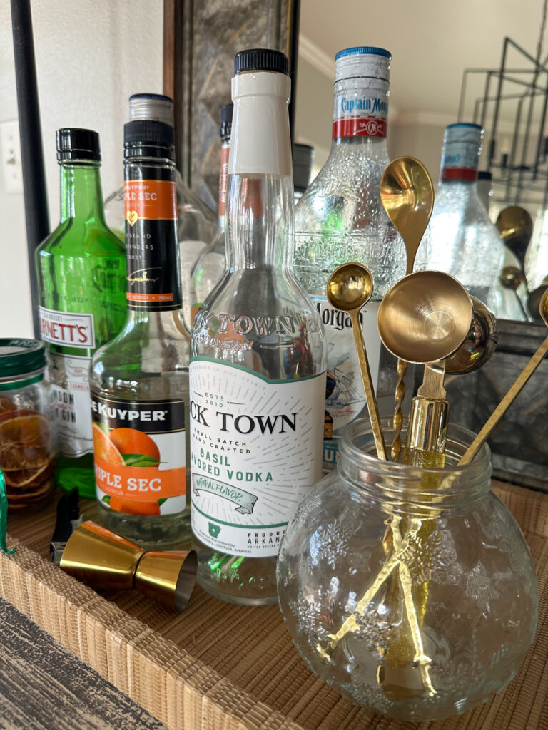 up close shot of bar tray on counter with gold stirrers and liquors