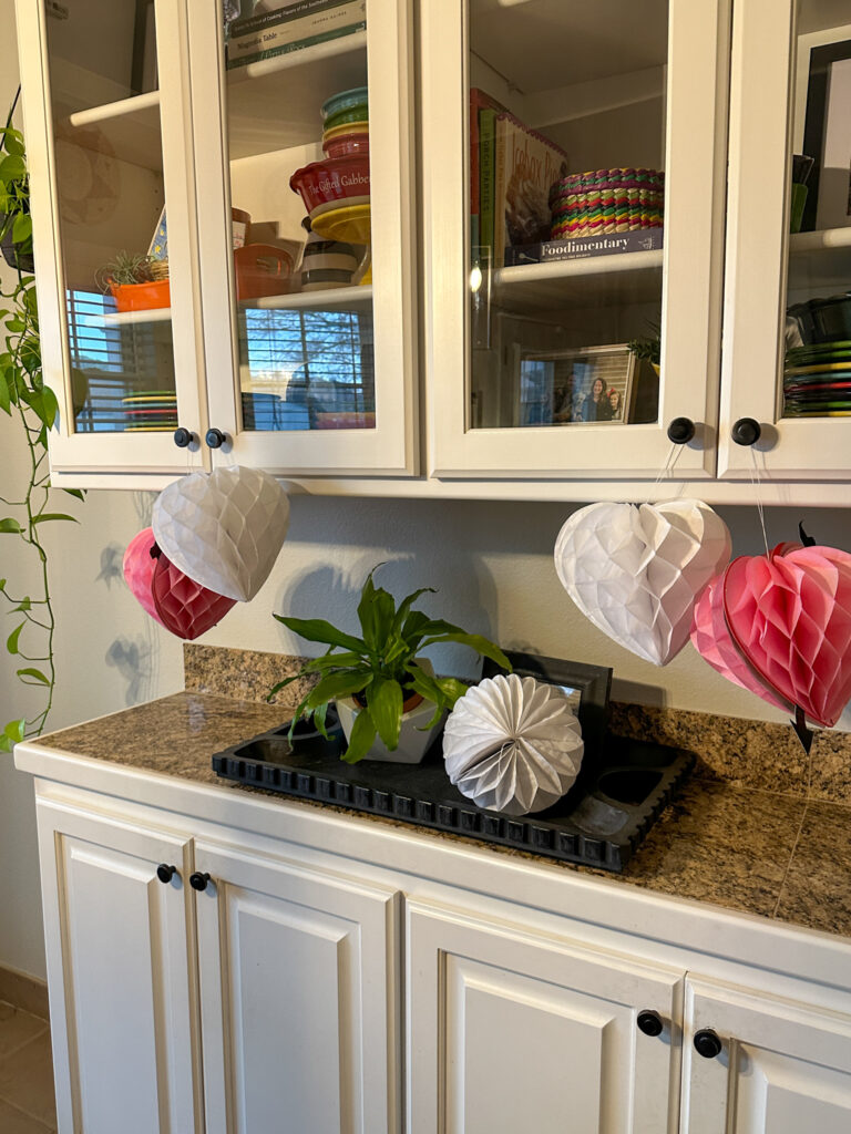 Valentine's Day decorations hanging from china hutch in kitchen