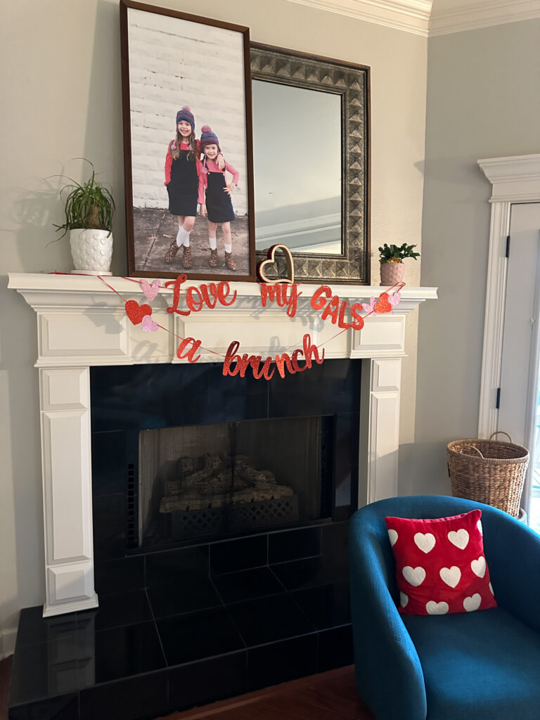 love my gals a brunch party banner for Galentine's Day hangs on mantel with photo and mirror