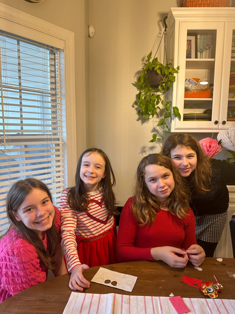 girls smile at mommy and me Galentine's brunch while doing crafts