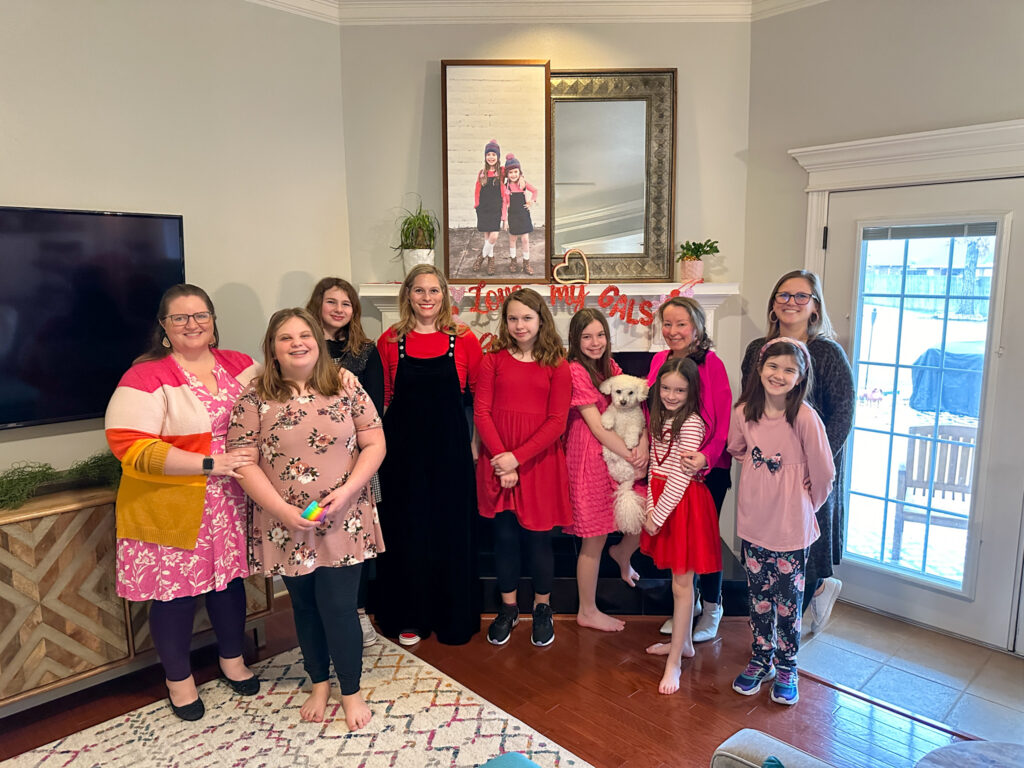 group of moms and daughters at mom and me Galentine's brunch pose in front of mantel