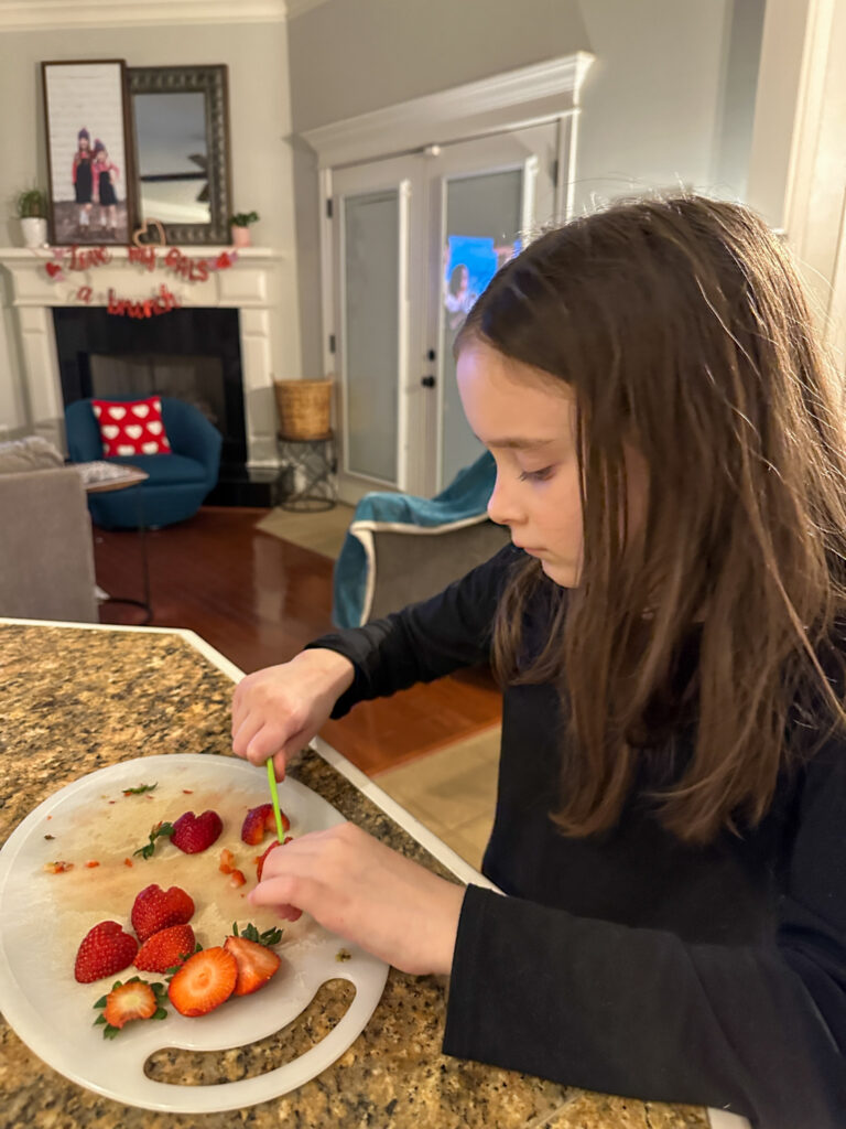 little girl chopping heart strawberries