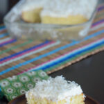 cream of coconut cake slice in front of full cake in back