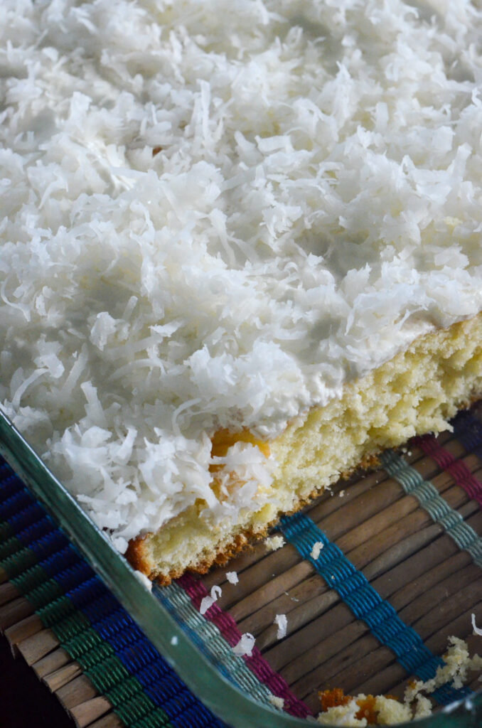 top down view of sliced coconut cake in glass pan