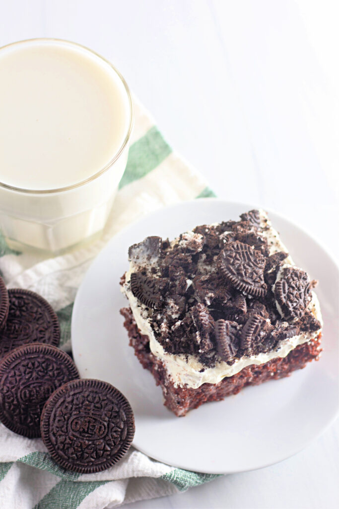 top down view of Oreo cookies and cream poke cake on white plate