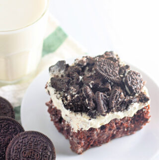 Oreo cookies and cream poke cake with Oreos and milk nearby