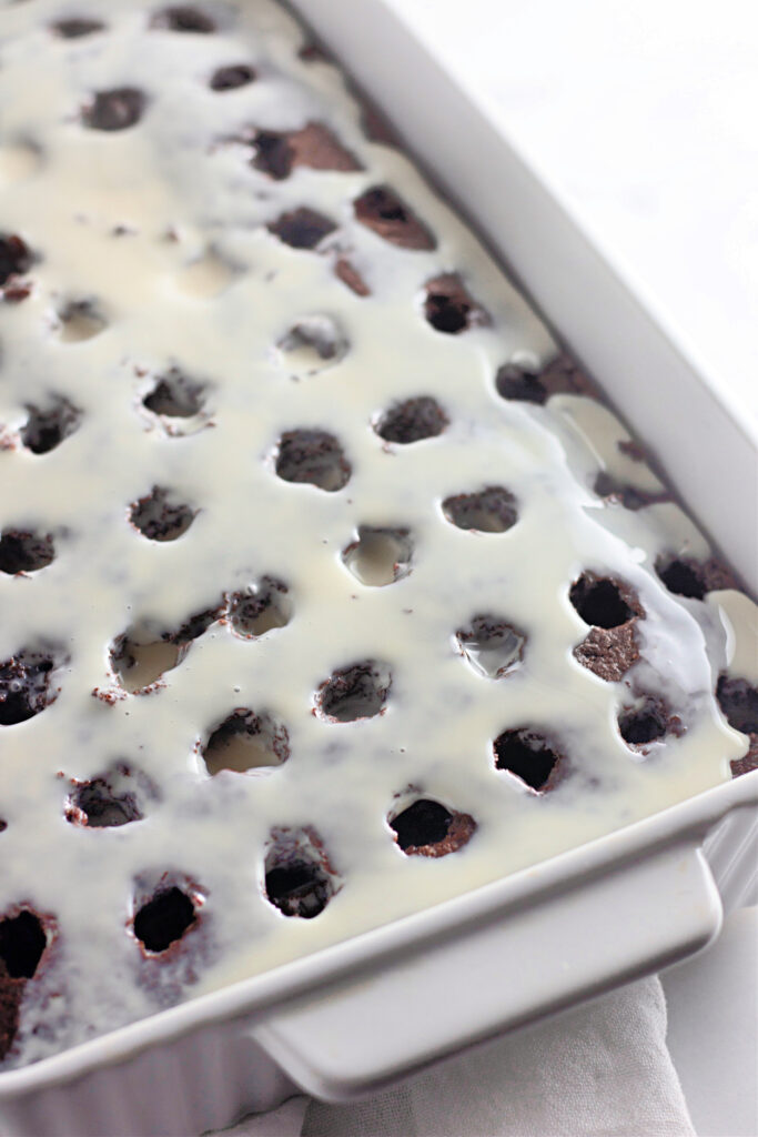 sweetened condensed milk topping over Oreo poke cake