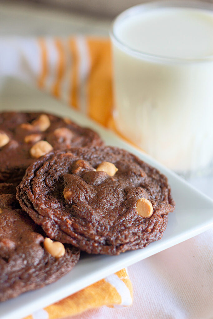 chocolate peanut butter chip cookies on white plate with orange napkin under