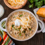 creamy chicken and wild rice chili with hominy in a white bowl on brown table