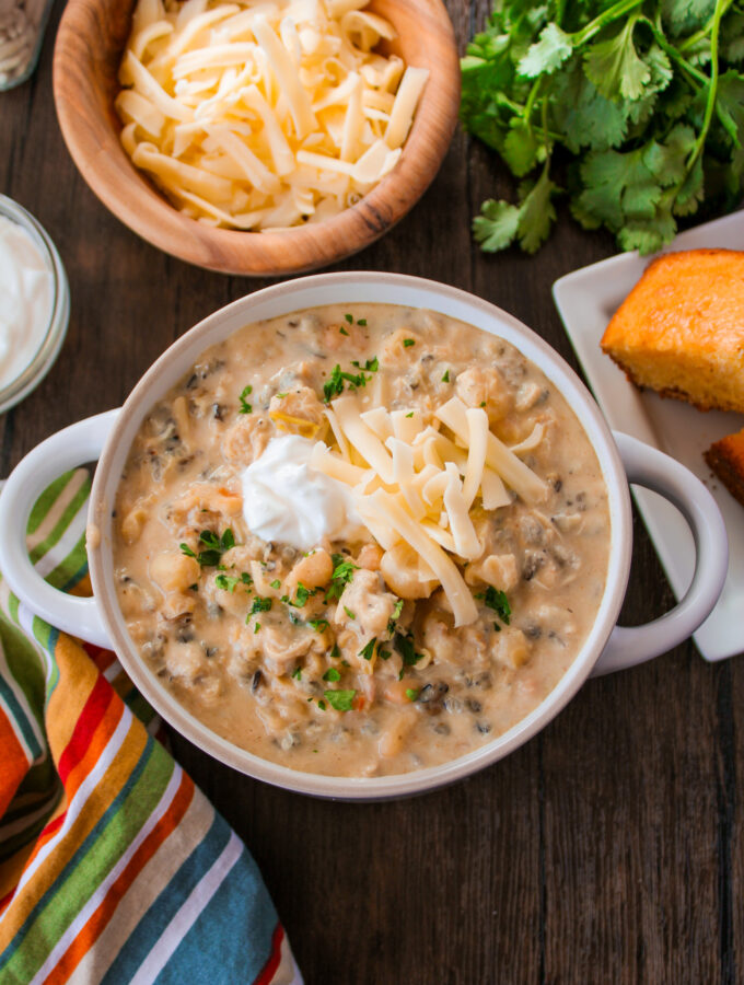 creamy chicken and wild rice chili with hominy in a white bowl on brown table