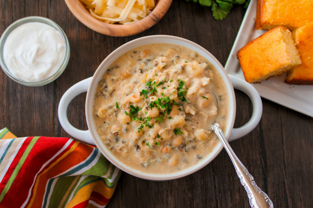 overhead shot of creamy chicken and wild rice chili with cornbread to the right on platter